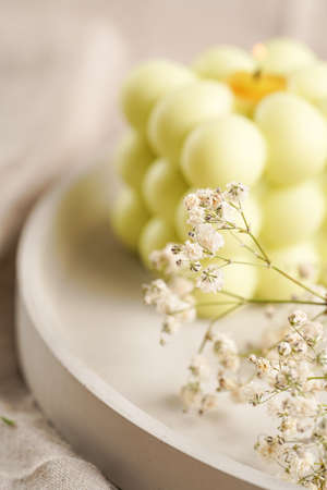 One white square bubble candle on a concrete tray on a linen table cloth with a mild focus on a blooming branchの写真素材