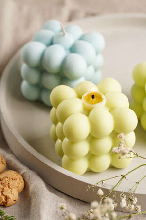 Green, blue and white square bubble candles on a concrete tray on a linen table clothの写真素材