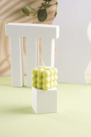 One off-white square bubble candle on a white cubeの写真素材
