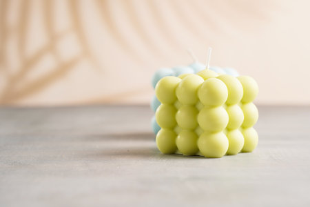Two light green and blue square bubble candles on a gray surfaceの写真素材