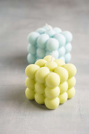 Two light green and blue square bubble candles on a gray surfaceの写真素材