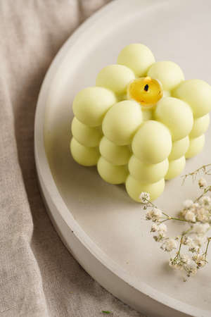 One white square bubble candle on a concrete tray on a linen table cloth with a blooming branch, close-upの写真素材
