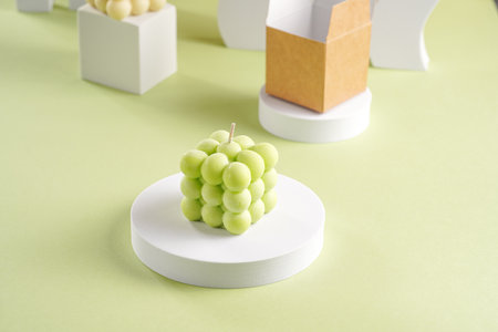 Blue, green and white square bubble candles on a pastel green surface and a packaging boxの写真素材