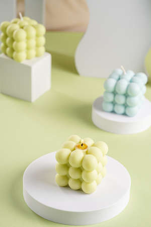 Three blue, green and white square bubble candles on a pastel green surfaceの写真素材