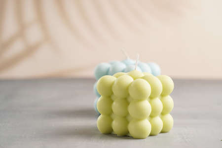 Two light green and blue square bubble candles on a gray surfaceの写真素材