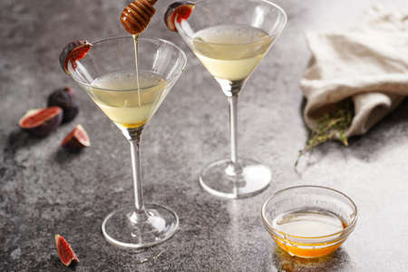 Two martini glasses with alcoholic beverage liquor with thyme branch, honey and figs on gray marble surfaceの写真素材