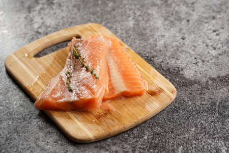 Two red raw salmon steaks on a wooden board on a gray marble surface, negative spaceの写真素材