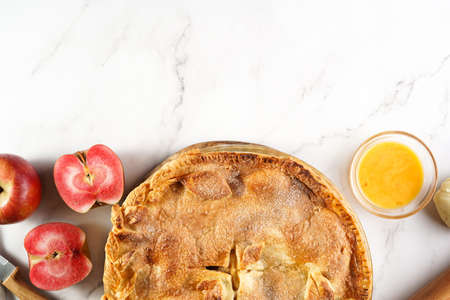 Classic traditional cinnamon apple pie and red flesh apples on a marble table, top view, negative spaceの写真素材