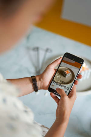 A girl taking photo of a bubble candle with her smart phoneの写真素材