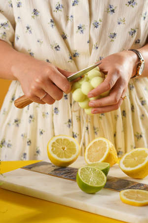 Female hands about to cut a bright green bubble candle surrounded by lemon and lime halves, fresh thymeの写真素材