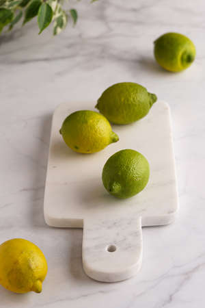 Several green and yellow lemons on a marble boardの写真素材