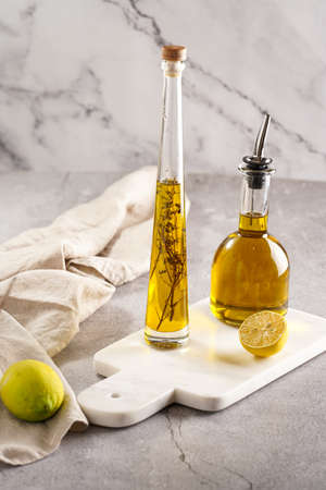 Two bottles with olive oil and fresh herbs - thyme - on white marble backgroundの写真素材
