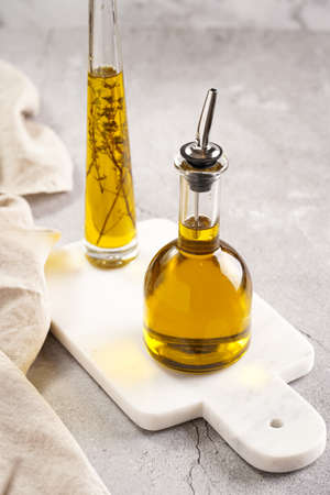 Two bottles with olive oil and fresh herbs - thyme - on white marble backgroundの写真素材