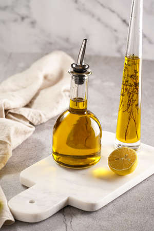 Two bottles with olive oil and fresh herbs - thyme - on white marble backgroundの写真素材