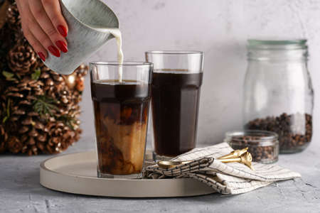 Pouring milk into a tall glass with cold coffee making frappe - iced cappuccinoの写真素材