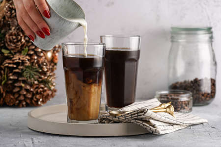 Pouring milk into a tall glass with cold coffee making frappe - iced cappuccinoの写真素材
