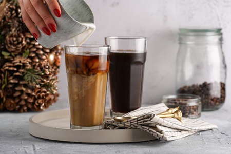 Pouring milk into a tall glass with cold coffee making frappe - iced cappuccinoの写真素材