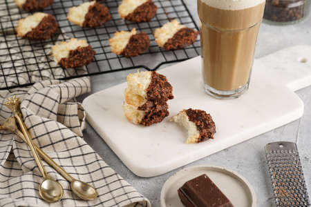 Several coconut flakes cookies dipped in chocolate on a white marble board and baking rack, christmas decorationの写真素材