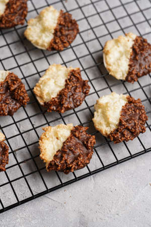 Several coconut flakes cookies dipped in chocolate on a baking rack on gray concrete surface, top viewの写真素材
