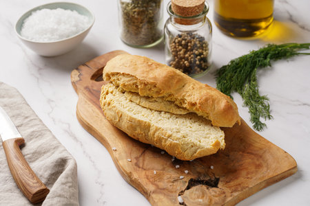 A loaf of homemade wheat bread on a wooden board on marble surfaceの写真素材
