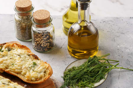 Cooking ingredients - olive and rapeseed oils, black and white pepper, dried herbs in small jars, green dill and bread sandwich with cheeseの写真素材