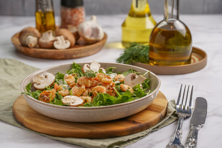 Arugula salad with shrimp and champignons, olive oil and dill on a wooden board on a white surfaceの写真素材
