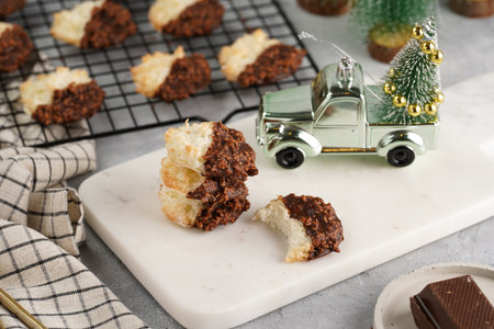 Several coconut flakes cookies dipped in chocolate on a white marble board and baking rack, christmas decorationの写真素材