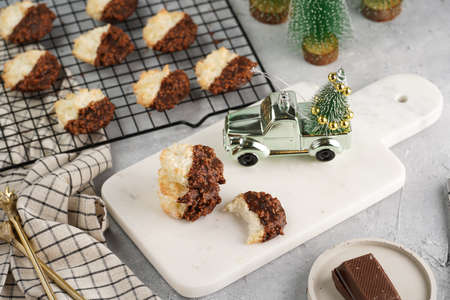 Several coconut flakes cookies dipped in chocolate on a white marble board and baking rack, christmas decorationの写真素材