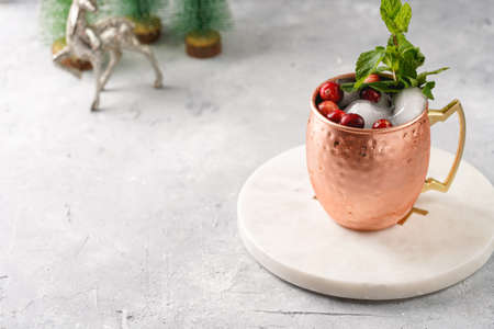 Traditional american alcoholic beverage moscow mule in copper mugs with cranberry and mint on white marble board - non-alcoholic cocktail version with christmas decorationの写真素材