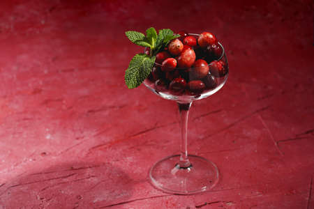 Wide champagne glass filled with fresh raw cranberries on a round marble tray, copy spaceの写真素材