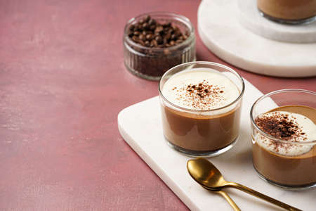 Italian chocolate and coffee mousse dessert semifreddo - half-frozen ice cream with whipped cream and cocoa powder in small glasses on purple surfaceの写真素材
