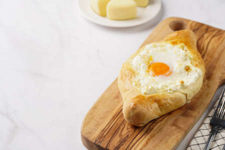 Traditional georgian dish of cheese-filled bread adjarian khachapuri with fried egg on a wooden...