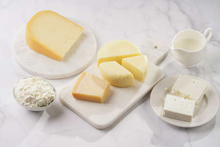Various cheese types on marble and porcelain plates - ingredients for traditional georgian open pie khachapuriの写真素材