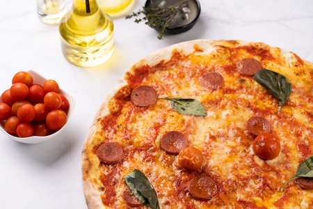 Freshly baked traditional mediterranean pizza with tomato sauce marinara, mozzarella cheese, pork sausage salsiccia and basilの写真素材