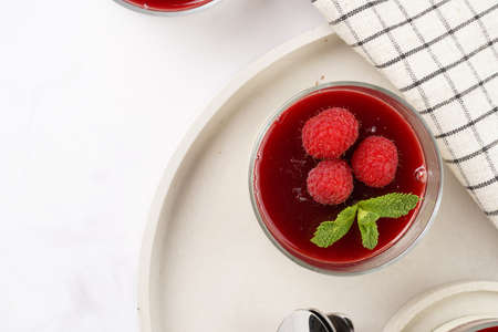 Italian dairy dessert panna cotta with raspberry jam, fresh raspberries and mint on round concrete trayの写真素材