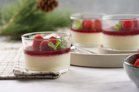 Italian dairy dessert panna cotta with raspberry jam, fresh raspberries and mint on round concrete trayの写真素材