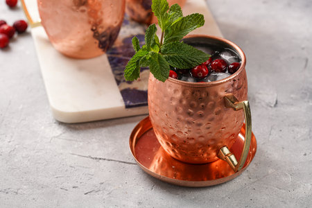 Traditional american alcoholic beverage moscow mule in copper mugs with cranberry and mint on white marble board - non-alcoholic cocktail versionの写真素材