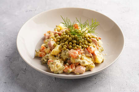 traditional east european dish for New Year's Eve - salad "Olivier" with potatoes, carrots, onion, peas, sausage, cucumbers, eggs and mayonnaise in a gray bowlの写真素材