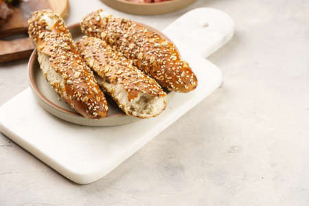 Savory breakfast ingredients: brown lye bread sticks garnished with oats and seeds, pork slices prosciutto, hard cheese gouda on marble boardの写真素材