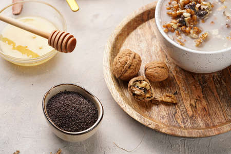 Traditional east european (ukrainian, polish, belarusian) religious christmas dish kutia made of wheat, poppy seeds, honey, walnuts and dried berries. modern style in porcelain bowls, wooden platesの写真素材