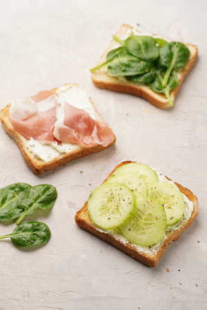 White toasts with cream cheese, ham, cucumbers and spinachの写真素材