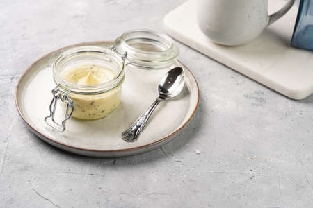 Mason jar with tasty herb butter with grated truffles on scandi plate on gray concrete surface