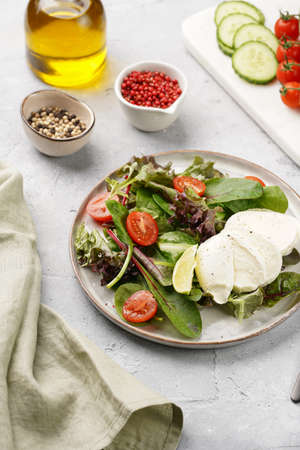 Salad with green leaves, lettuce, spinach, cherry tomatoes, mozzarella, olive oil, chilli pepper,...