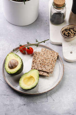 Ingredients for Healthy crunchy crisp bread sandwich: avocado, crackers and cherry tomatoes on round...