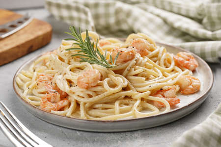 Flat plate with pasta spaghetti with heavy cream and roasted shrimps with garlic sauce and parmesan cheese on gray concrete surfaceの写真素材