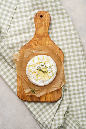 Oven baked camembert cheese with lye baguette bread on wooden board, gray concrete surface. Homemade grilled brie with thyme, rustic style table settingの写真素材