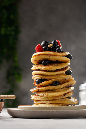 Fitness blueberry pancakes with protein, raspberries and walnuts stacked on top of each other on light gray backgroundの写真素材