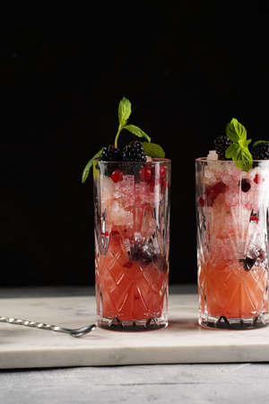 Two long glasses with non-alcoholic mocktail version of the classic blackberry and gin cocktail...