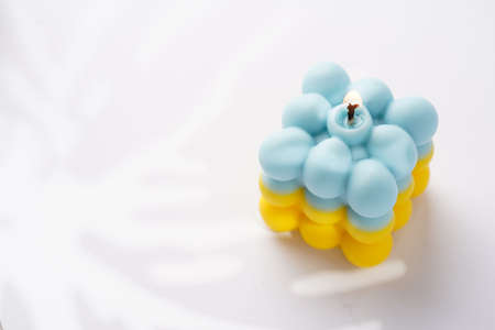 One patriotic bubble candle - half blue, half yellow on white seamless surface with starry light shadowsの写真素材