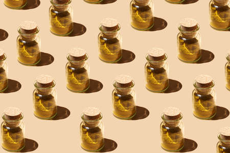 A hard light pattern of a glass jar with cork lids containing curry spice on pastel yellow seamless...